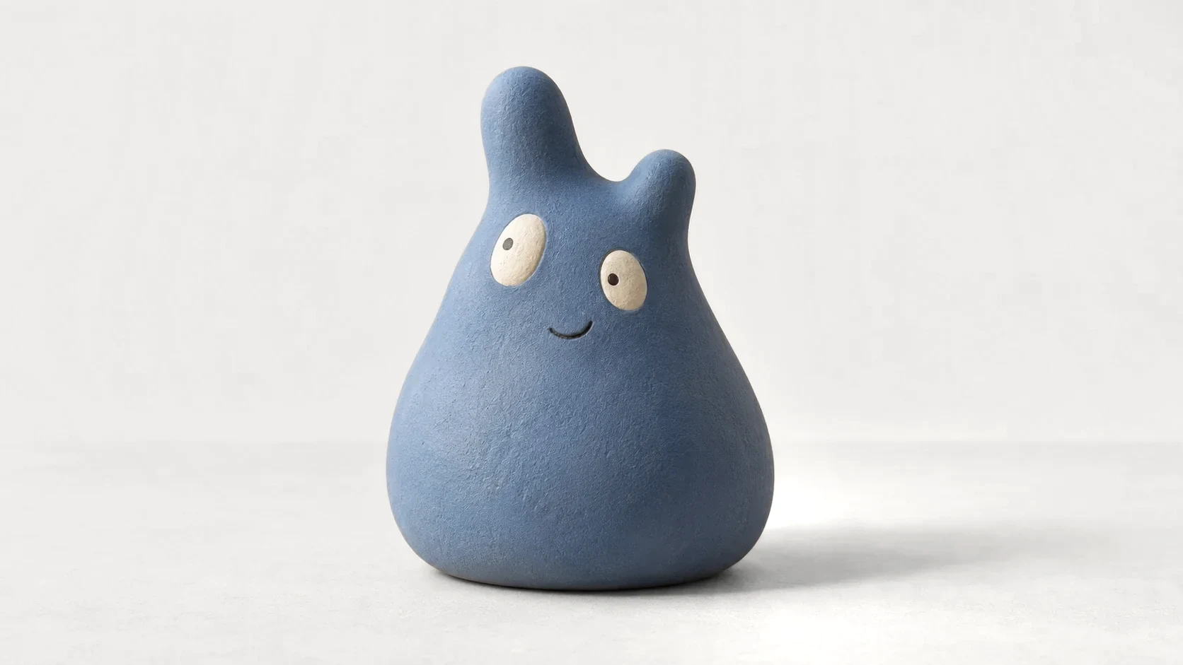 Una piccola scultura blu opaca, tonda e con due orecchie diverse, nata dal disegno di un bambino.